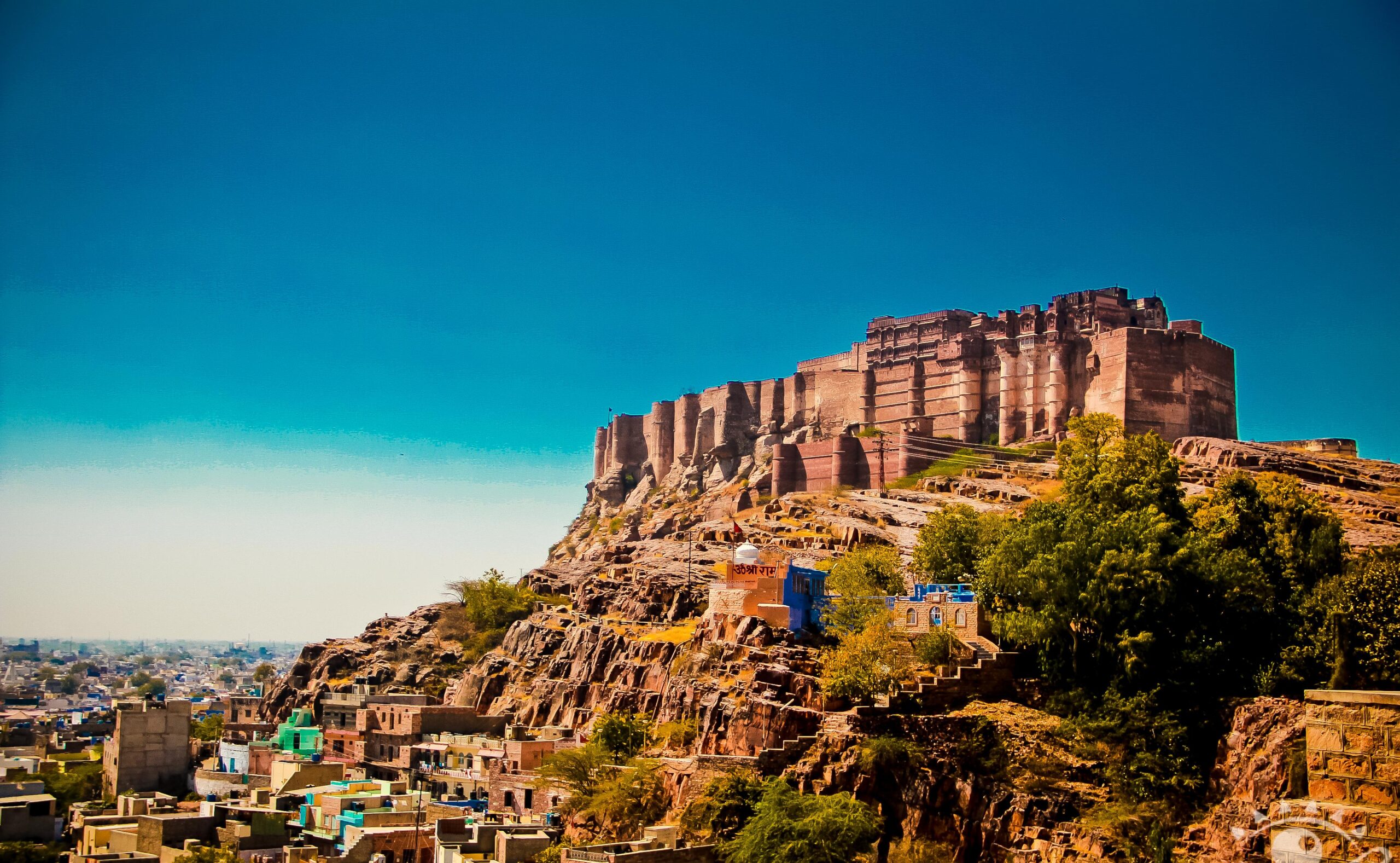Mehrangarh Fort in Jodhpur standing atop a rocky hill with blue houses below
