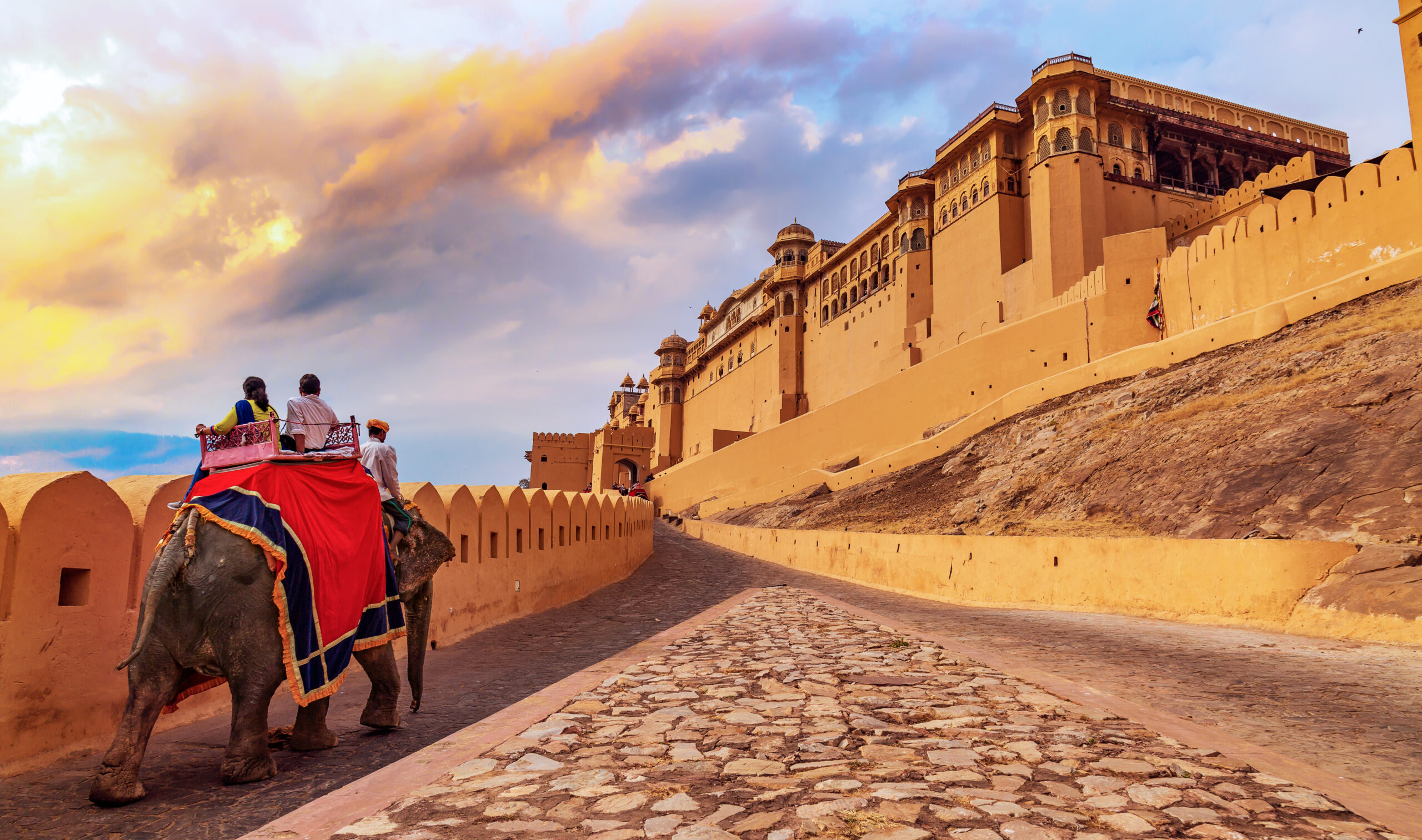 Amer Fort in Jaipur with tourists riding an elephant on the cobbled pathway at sunset