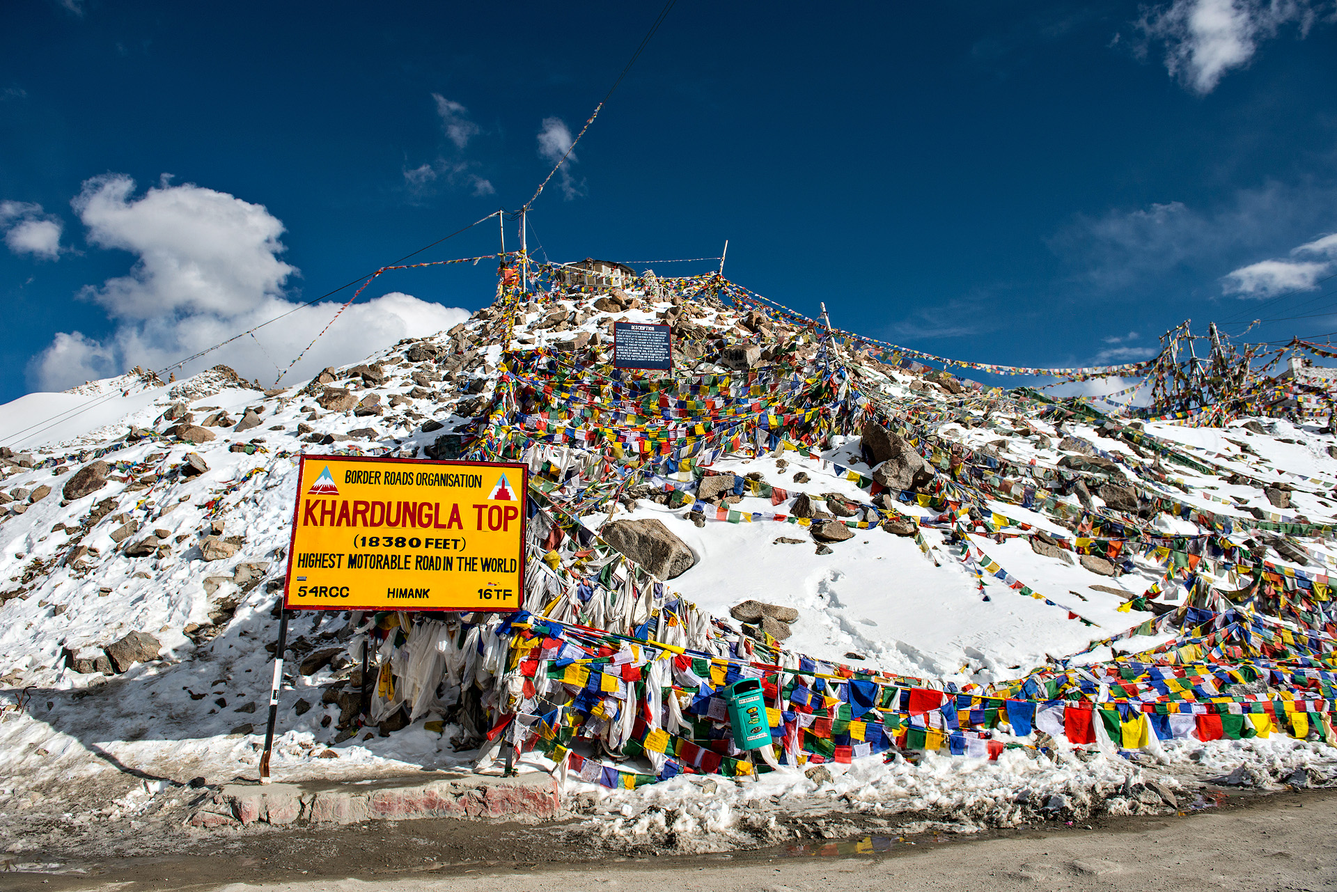 Khardung La Pass in Ladakh with snow-covered mountains and road sign
