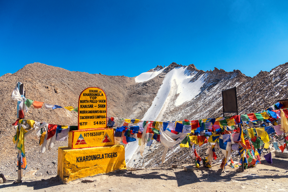 Khardung La Pass in Ladakh with snow-covered mountains and road sign